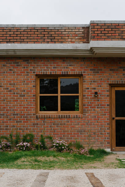 Brick House Facade with Wooden Window and Flower Bed