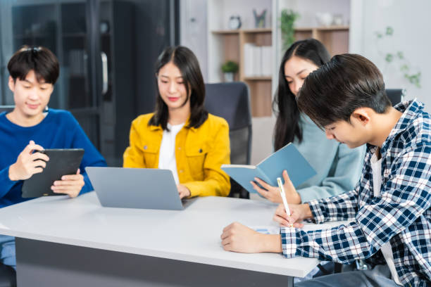 istock university classroom, diverse group of young students Asian collaborate study together, sharing smiles and insights around desks, exemplifying the joy of learning and friendship in higher education. 2155868199