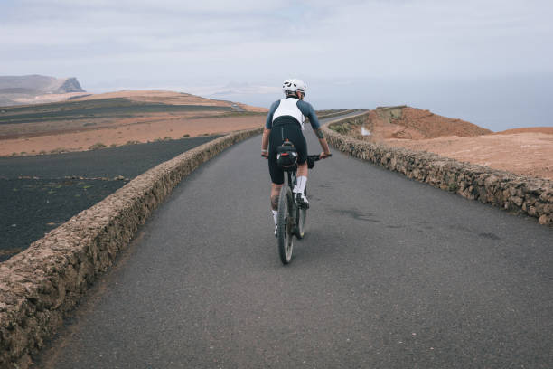 istock Road bicyclist rides through desert landscape 2155868489