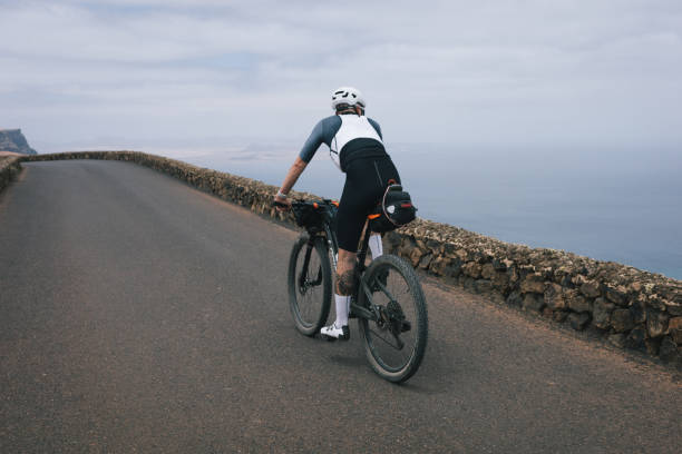 istock Road bicyclist rides through desert landscape 2155868572