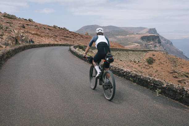 istock Road bicyclist rides through desert landscape 2155868593