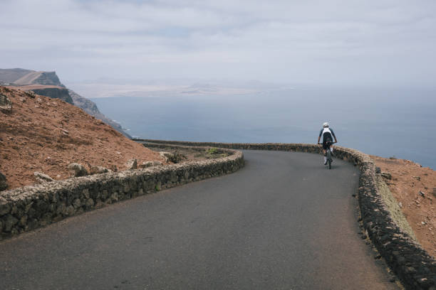 istock Road bicyclist rides through desert landscape 2155868666