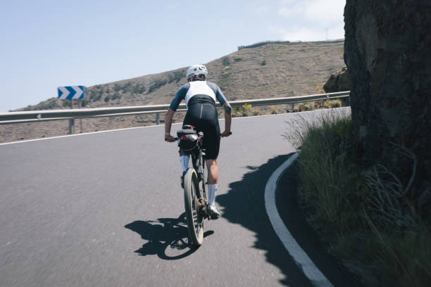 istock Road bicyclist rides through desert landscape 2155869020