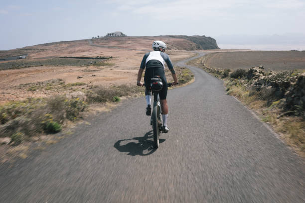 istock Road bicyclist rides through desert landscape 2155869112