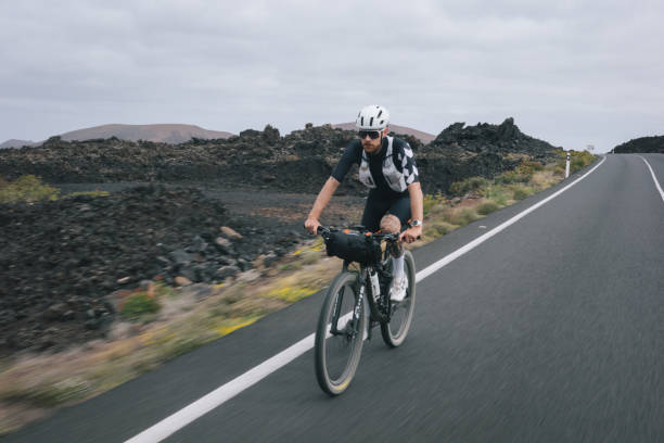 istock Road bicyclist rides through desert landscape 2155869544