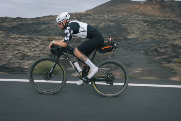 istock Road bicyclist rides through desert landscape 2155869727