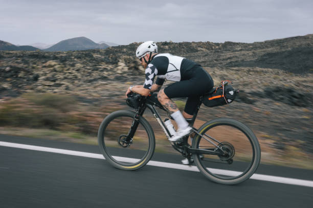 istock Road bicyclist rides through desert landscape 2155869730