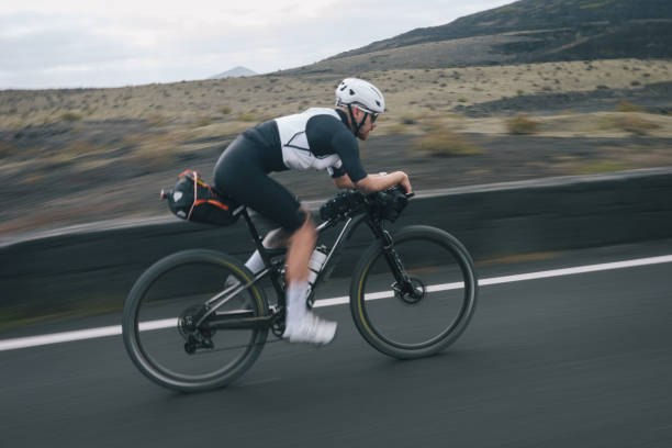 istock Road bicyclist rides through desert landscape 2155869882