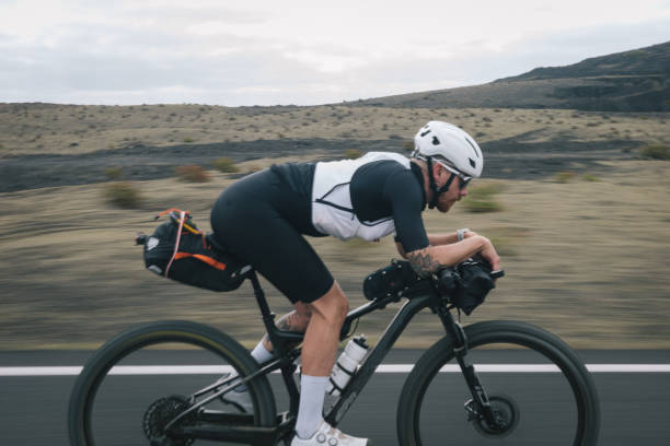 istock Road bicyclist rides through desert landscape 2155869921
