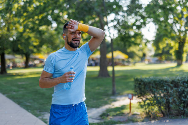 istock Man wiping sweat with wristband holding bottle 2155870286