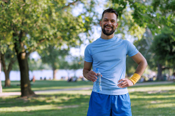 istock Man in park with water bottle standing 2155870403