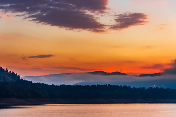 The Ceahlau mountain silhouette against a sunset sky over water