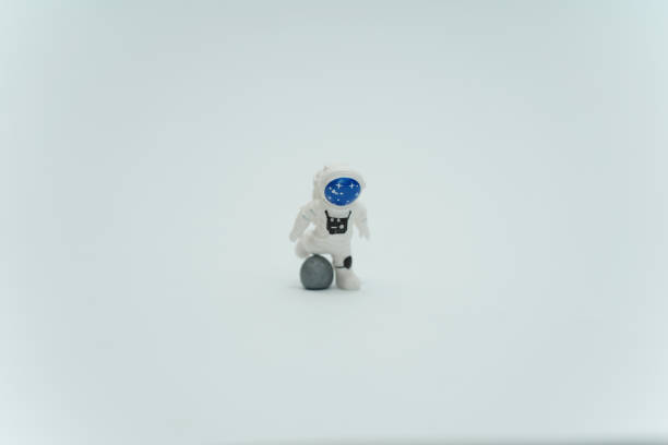 A plastic toy astronaut kicking to the moon on a white background the concept of space, moon and spaceman