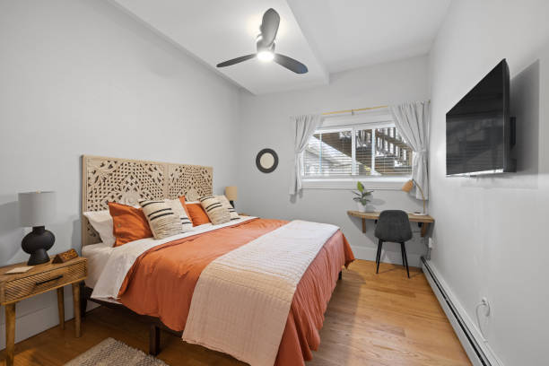 a room with a bed, television, windows and wood floors