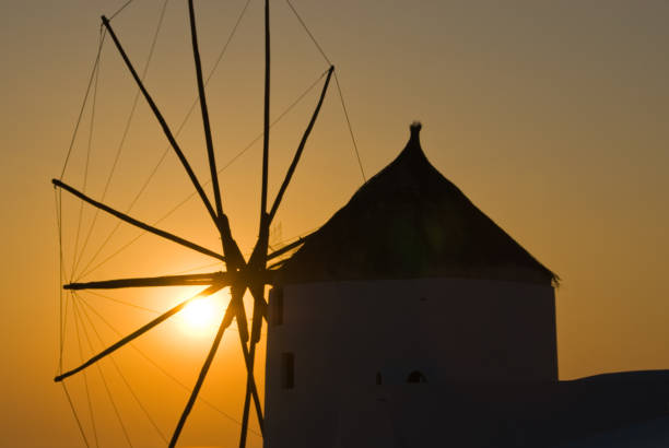 Oia, Greece – May 11, 2011: A silhouetted windmill against the setting sun in Oia, Greece