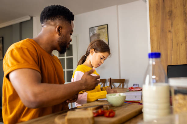 istock Girl is doing homework in the kitchen while her father preparing breakfast at home. 2155876006