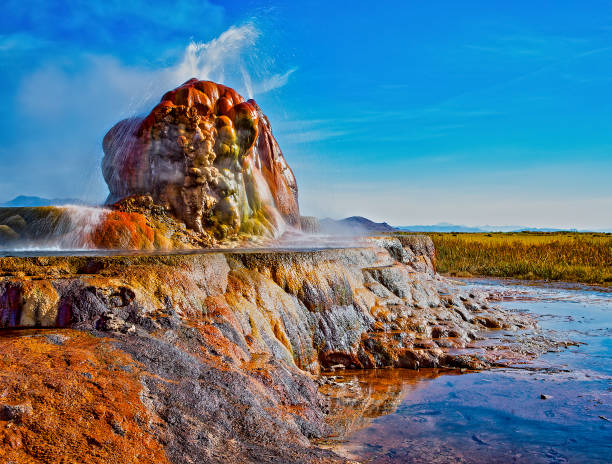 A big hot spring with steam rising from water: Fly Geyser. Nevada