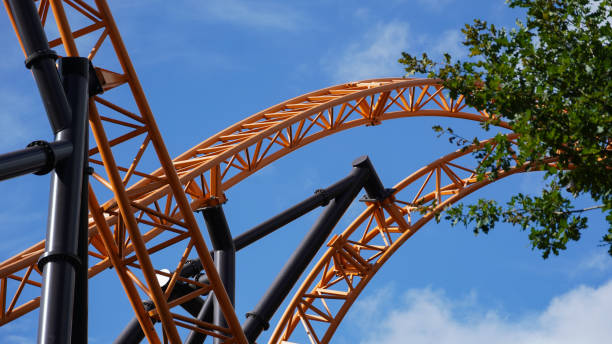 istock Orange-coloured roller coaster tracks of an extreme roller coaster, crossing under a blue sk 2155876619