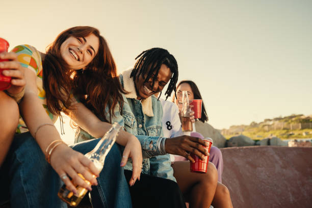 istock Happy young friends laughing and enjoying drinks outdoors on a sunny day 2155877215
