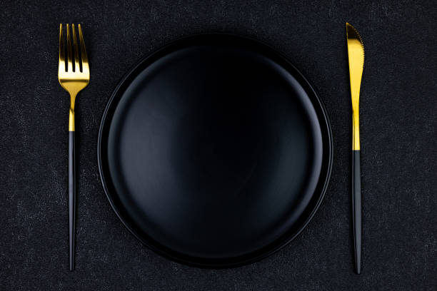 istock Empty black plate with fork and knife on black concrete background, top view 2155877681