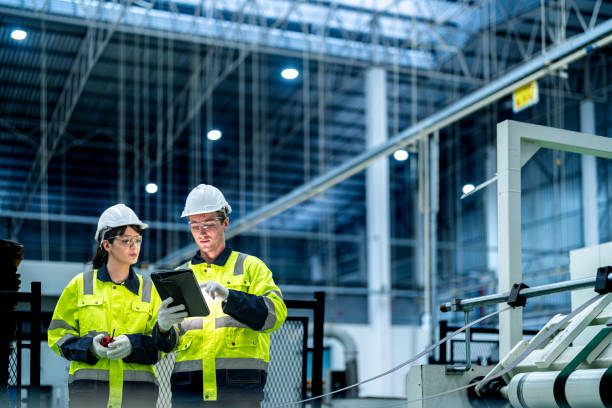 Male and female engineers in neat work clothes prepare and control the production system of large modern machines in a factory producing industrial technology products. Male and female engineers in neat work clothes prepare and control the production system of large modern machines in a factory producing industrial technology products. manufacturing occupation stock pictures, royalty-free photos & images