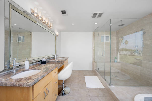 istock Spacious white bathroom with stone countertop, lit by sleek chrome fixtures 2155877853