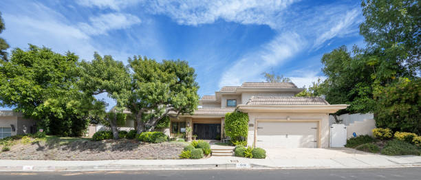 istock the front view of a home surrounded by trees and bushes 2155879549