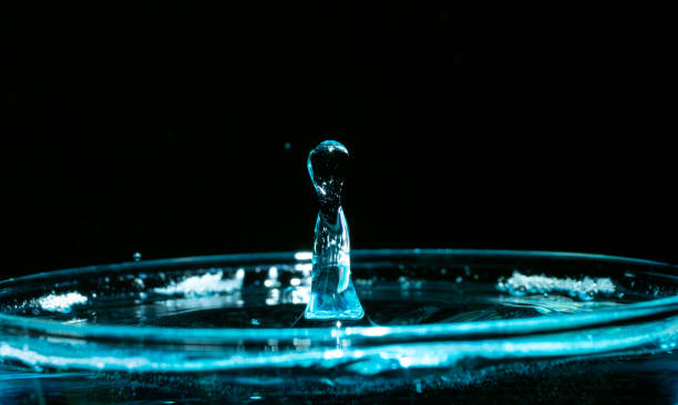 istock Droplets falling into a glass of water against dark backdrop 2155881217