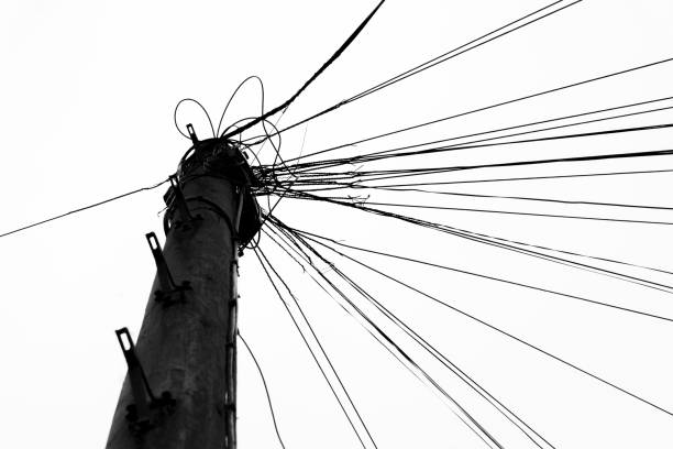 Tangled telephone lines converge on a single utility pole.