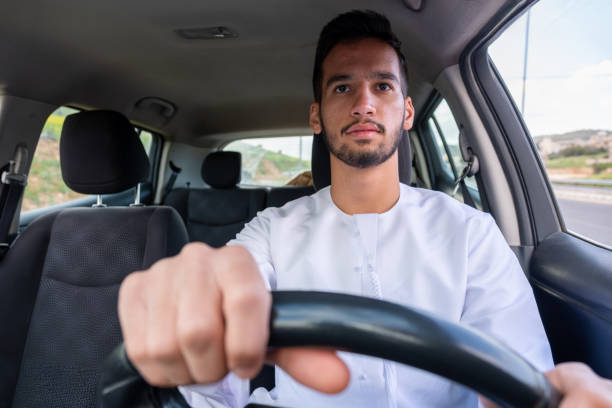 istock A cheerful young man with a beard, wearing a traditional Middle-Eastern outfit, smiles confidently while seated in his car. He appears to be enjoying a drive through a scenic countryside 2155883286