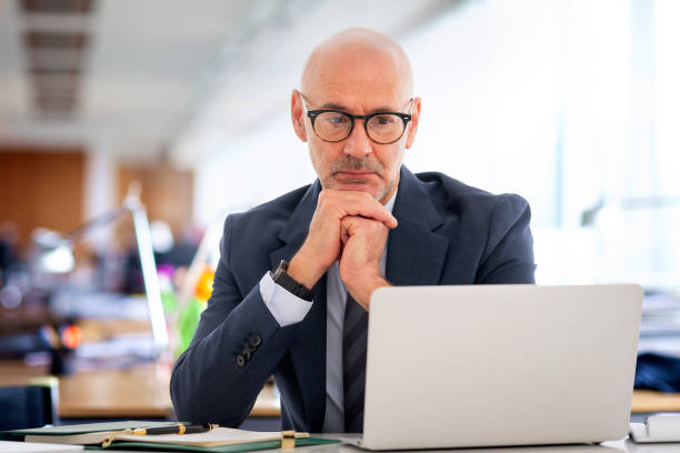 istock Businessman sitting at the office and looking at the computer thoughtfully 2155883491