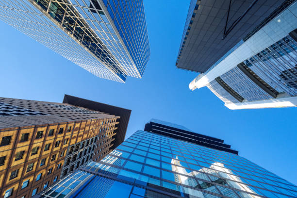 Low angle view of modern skyscrapers in Frankfurt, Germany, showcasing impressive architecture against clear blue sky.