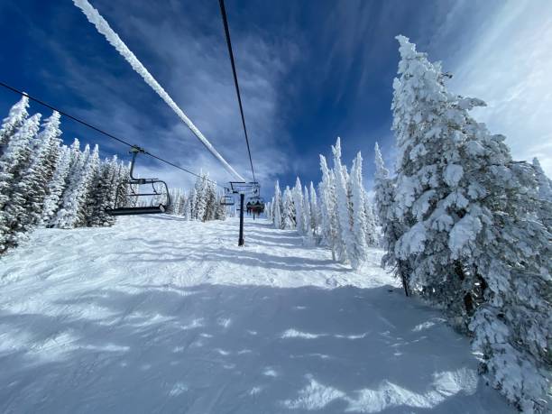 istock Ski lift ascending a snowy hill surrounded by snow-covered trees 2155891171