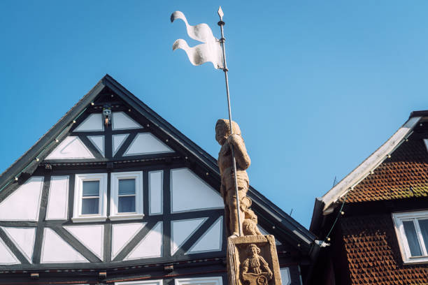 A picturesque scene of a historic town square in Fritzlar, Germany, featuring a medieval statue and traditional half-timbered houses.