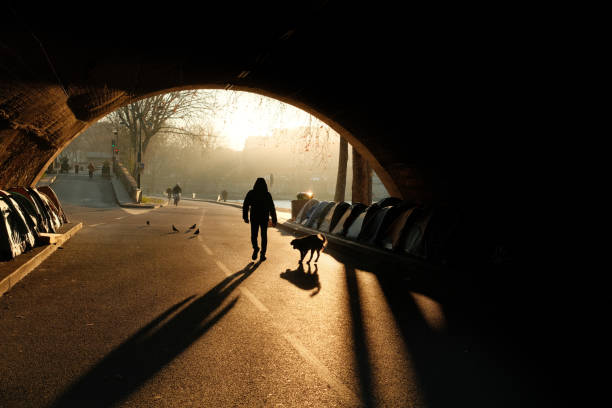Paris, France – April 24, 2024: A woman walks through a tunnel while holding a dog in her hand
