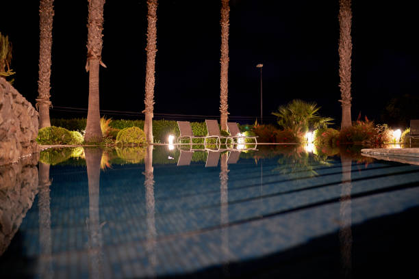 istock Table by a pool with palm trees reflections in the foreground 2155892570