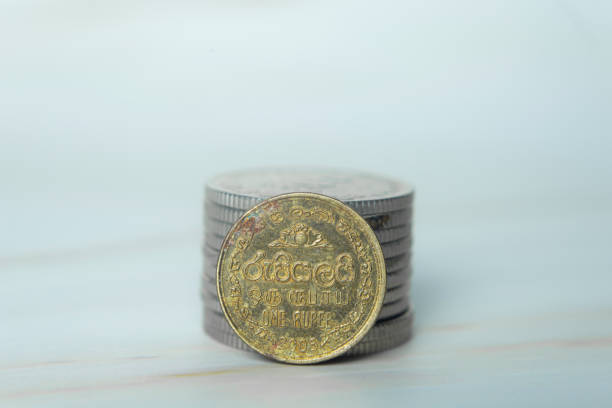 Heaps of money or pile of gold colored golden currency coins arranged as mountain or set or stacks of abundant money placed on a wooden surface over beige gray colored horizontal background with copy space
