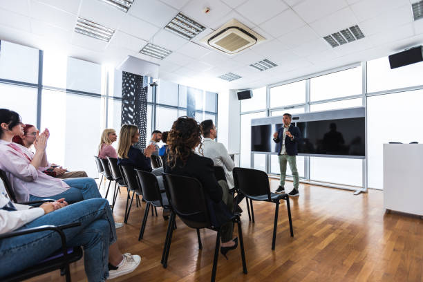 istock Multiracial group of entrepreneurs attending a seminar in multimedia classroom with smart board. Applauding their Asian CEO. 2155893887