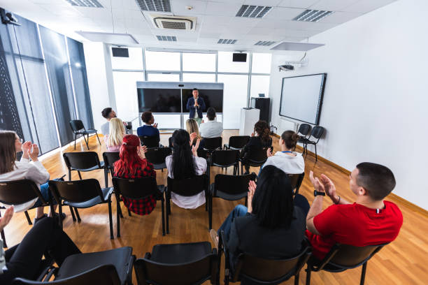 istock Multiracial group of entrepreneurs attending a seminar in multimedia classroom with smart board. Applauding their Asian CEO. 2155893888