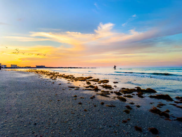 istock Single man on tropical island beach over orange color sunset sky 2155895492