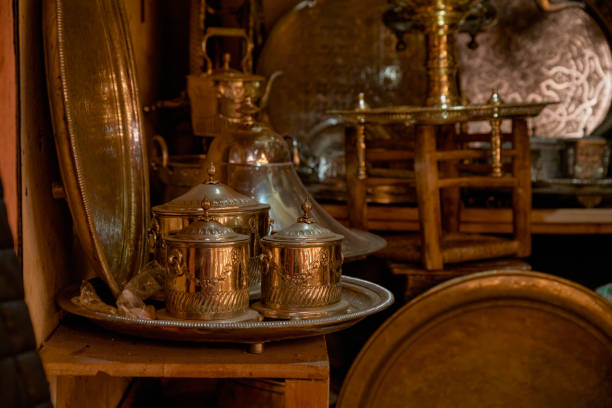 A collection of ornamental metal objects and utensils, possibly antiques, in a subdued environment