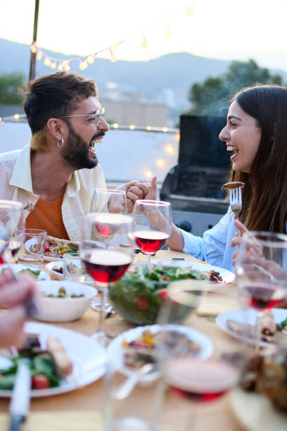 istock Laughing Caucasian young couple sitting at table having fun during celebration barbecue outdoors. 2155896870