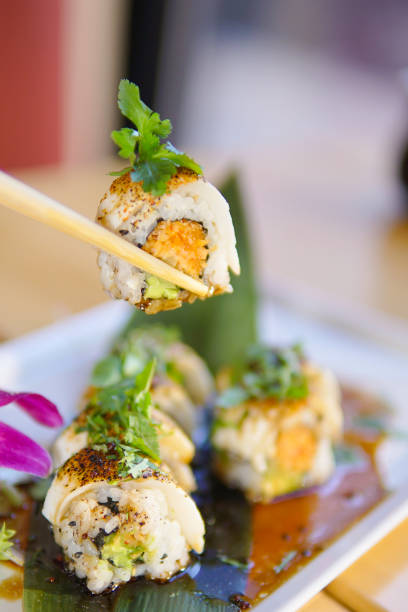 A person picking up sushi with chopsticks from a plate