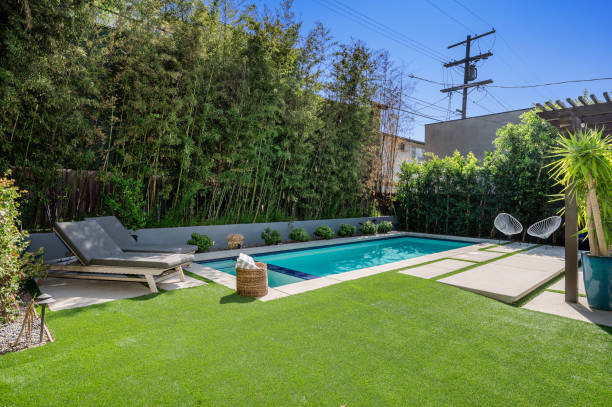 a backyard swimming pool surrounded by green lawns and trees