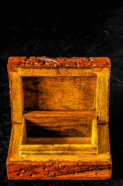 A wooden box with a brown lid is sitting on a black surface. The box is empty and has a natural, rustic appearance