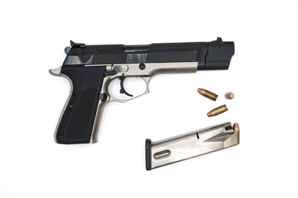 Detail of a nice police pistol with the magazine and some 9 mm bullets with a truncated cone tip on a white background.