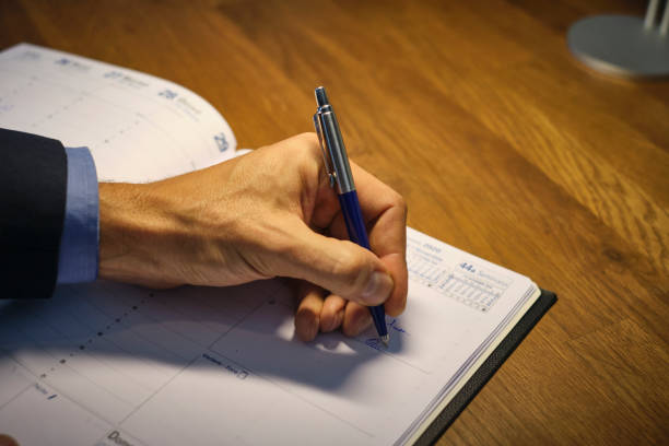 A hand holding a pen writing on a journal