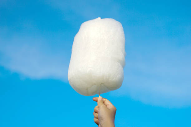 istock holding white cotton candy on sky background. Cotton candy made from sugar spun into thin noodles. Like a cloud, many colors depending on the color. Soft and selective focus. 2155904105