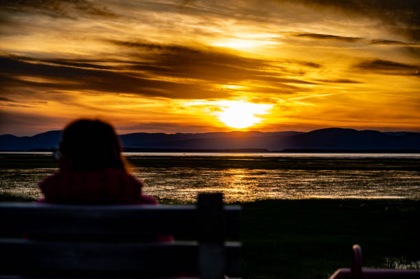 Woman looking at sunset over St. Lawrence river in Montmagny, Quebec, Canada, during summer