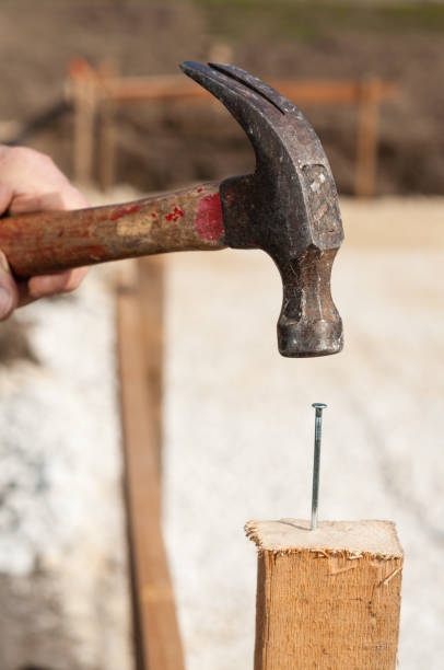 istock Man using a hammer for nailing on a construction site in southern Germany 2155908199